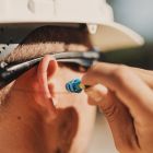A worker wearing SoundShield safety glasses inserting the earplugs into his ear